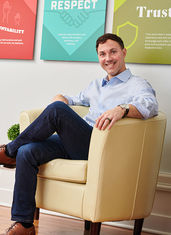 Todd Bertsch sitting in chair with core values on wall